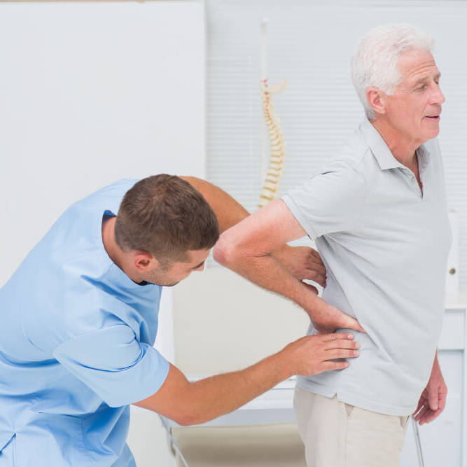 Home 9 A healthcare professional assisting an elderly man with back pain during a consultation.